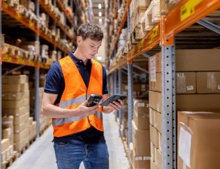Operador en almacén consultando sistema WMS con inventario integrado en tiempo real