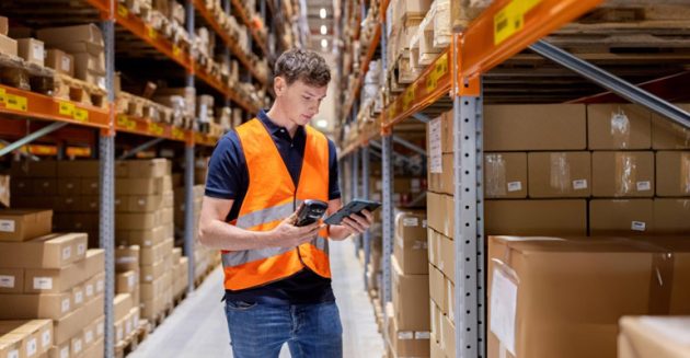 Operador en almacén consultando sistema WMS con inventario integrado en tiempo real