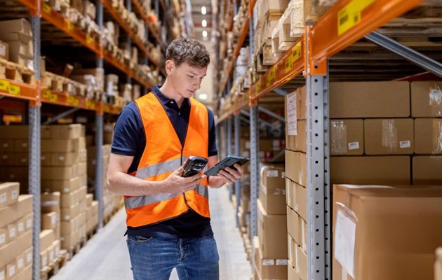 Operador en almacén consultando sistema WMS con inventario integrado en tiempo real