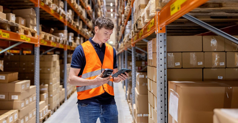 Operador en almacén consultando sistema WMS con inventario integrado en tiempo real